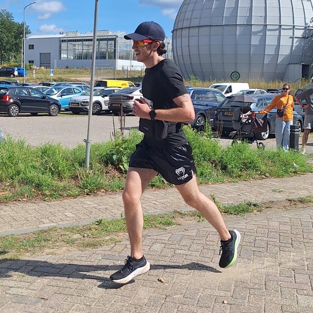 Sven in zwart shirt en pet, rennend over een klinkerpad tijdens de Heiderun in Ede